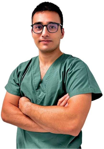 Portrait d’un médecin en tenue verte, les bras croisés, sur fond neutre.