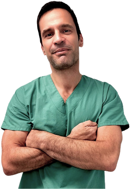 Portrait d’un médecin en tenue verte, les bras croisés, sur fond neutre.