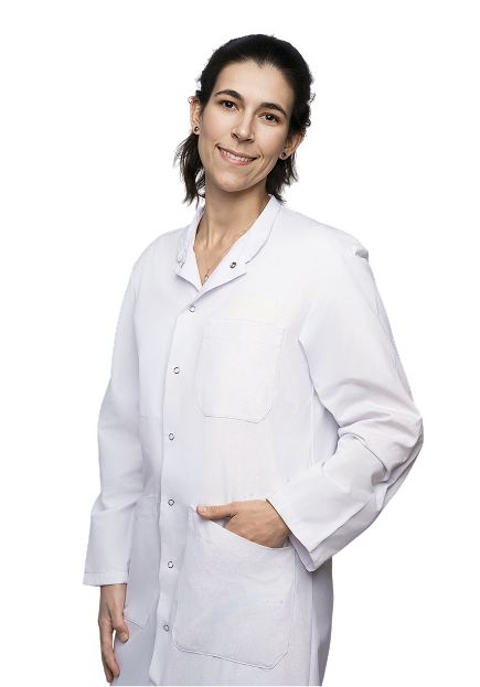 Portrait d’une professionnelle de santé en blouse blanche, debout et souriante.
