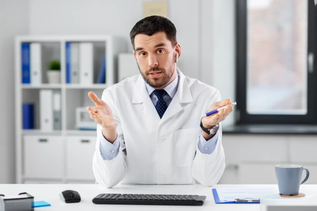 Un médecin en blouse blanche parle face caméra, en contexte pédagogique.