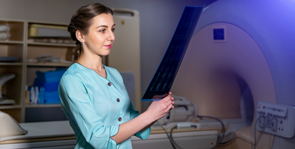Une technicienne médicale examine une radiographie sur un écran lumineux.