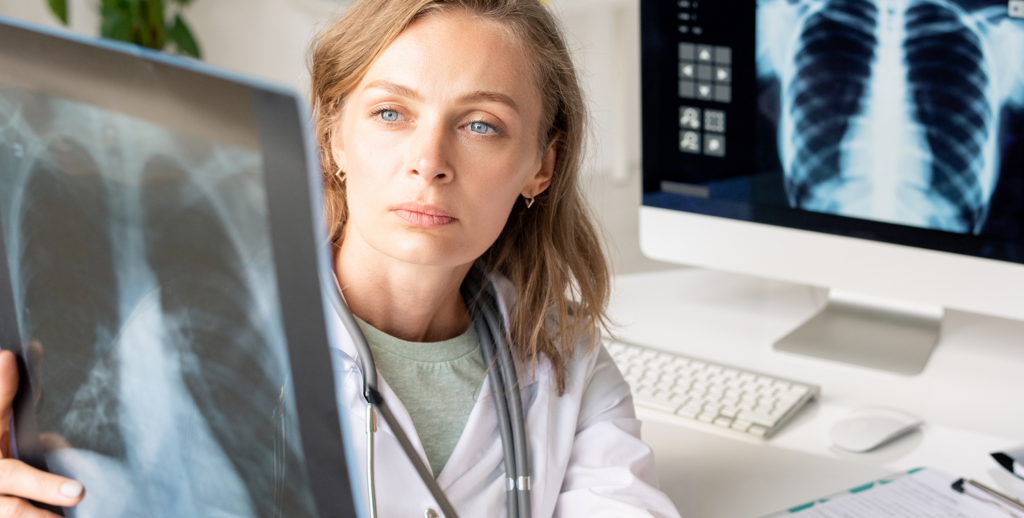 Portrait d’une professionnelle de santé en blouse blanche, assise devant du matériel médical.