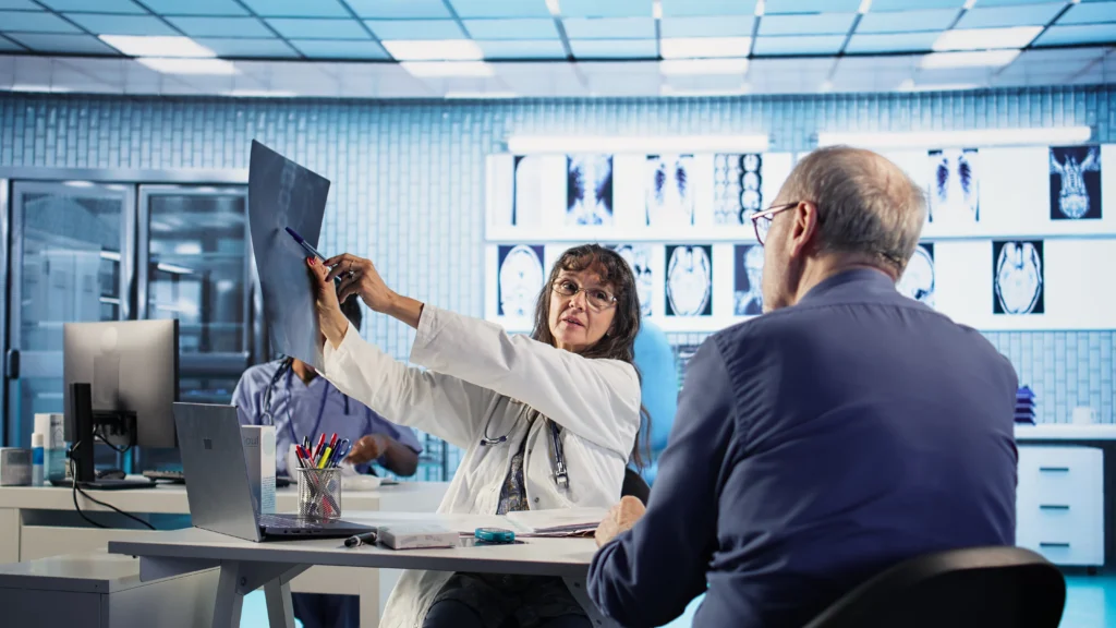 Un médecin discute avec un patient en consultation, en cabinet.