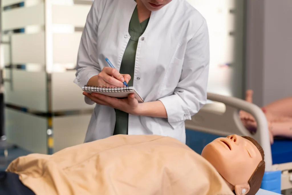 Une soignante prend des notes près d’un patient allongé sur un lit médical.