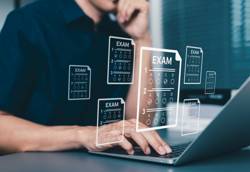Candidat devant un ordinateur portable avec des feuilles d’examen QCM : annales EVC à télécharger et à utiliser
