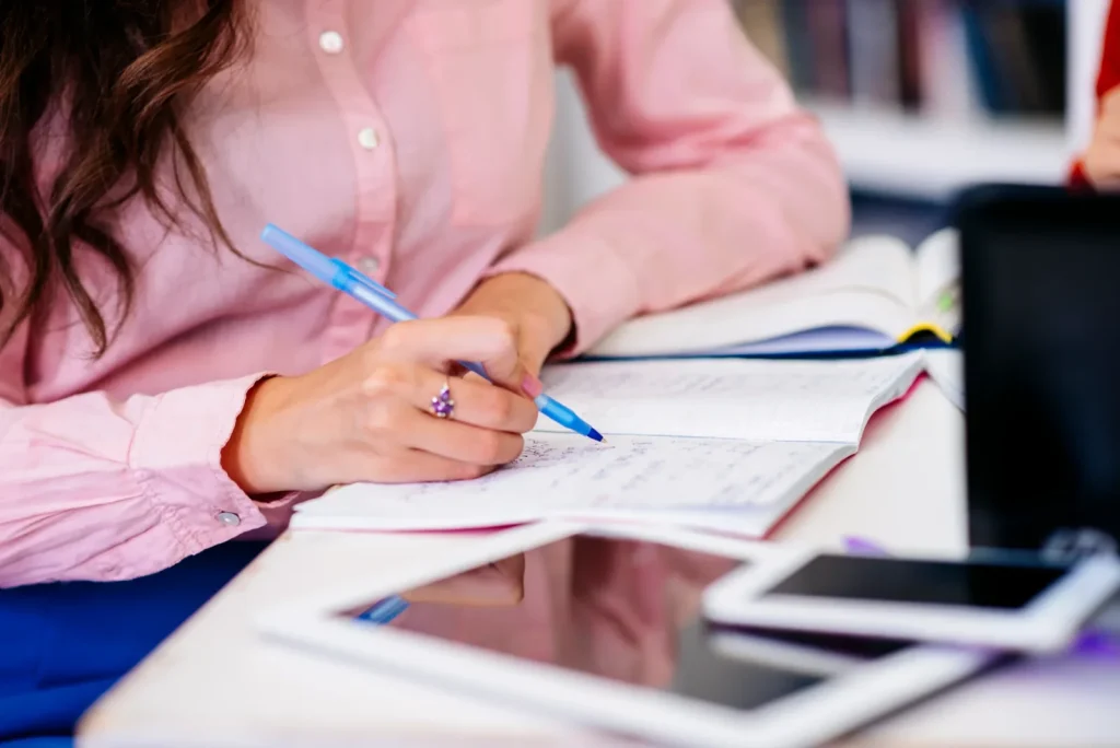 Candidat qui écrit au stylo dans un cahier pour une épreuve, illustrant la préparation et le jour J des EVC à Rungis