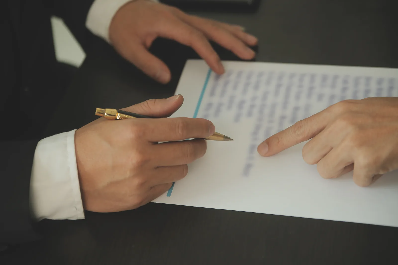 Mains signant et relisant un dossier administratif, pour illustrer la procédure de reconnaissance de diplôme de médecine en Suisse auprès de la MEBEKO